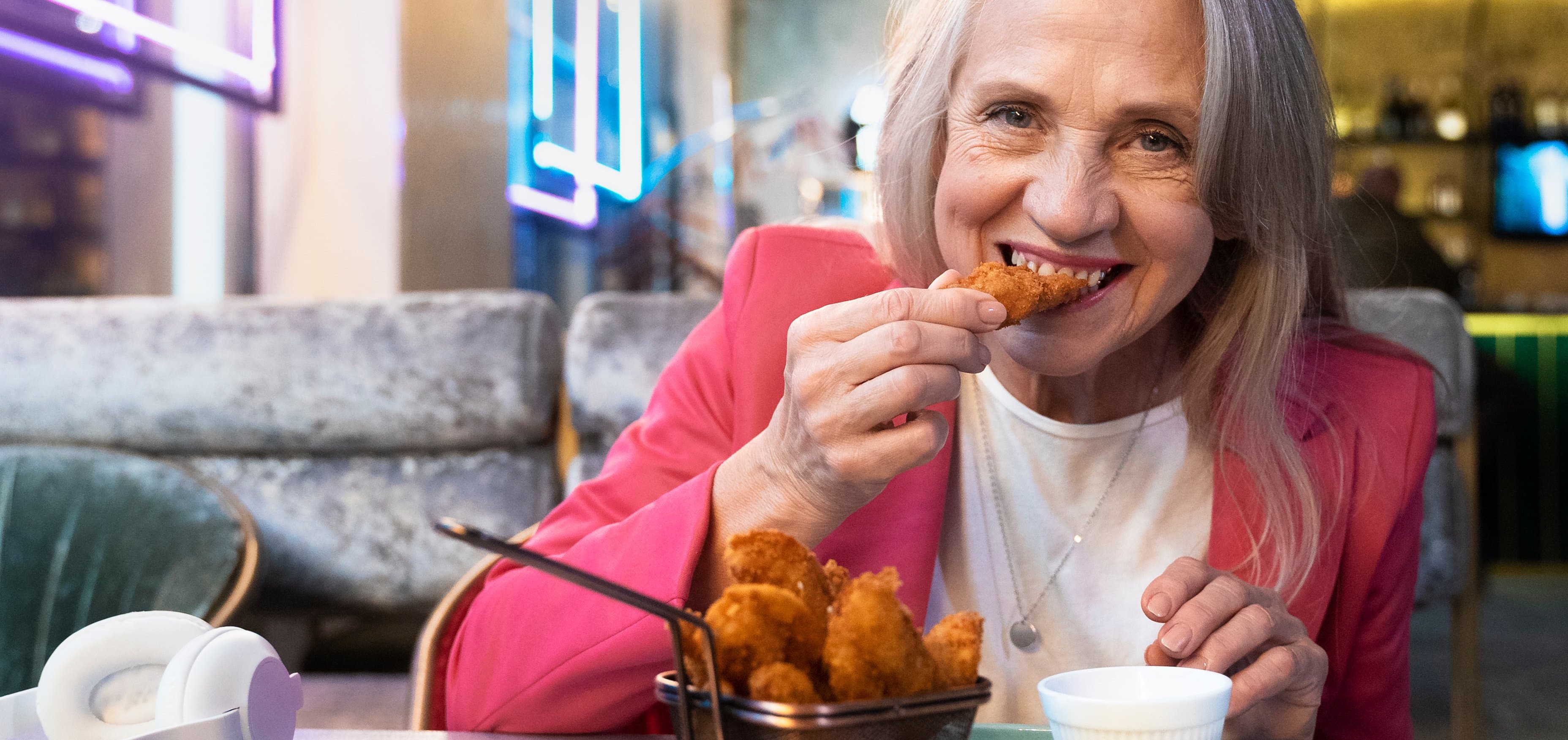 A smiling guest biting into a Crispo’s chicken tender