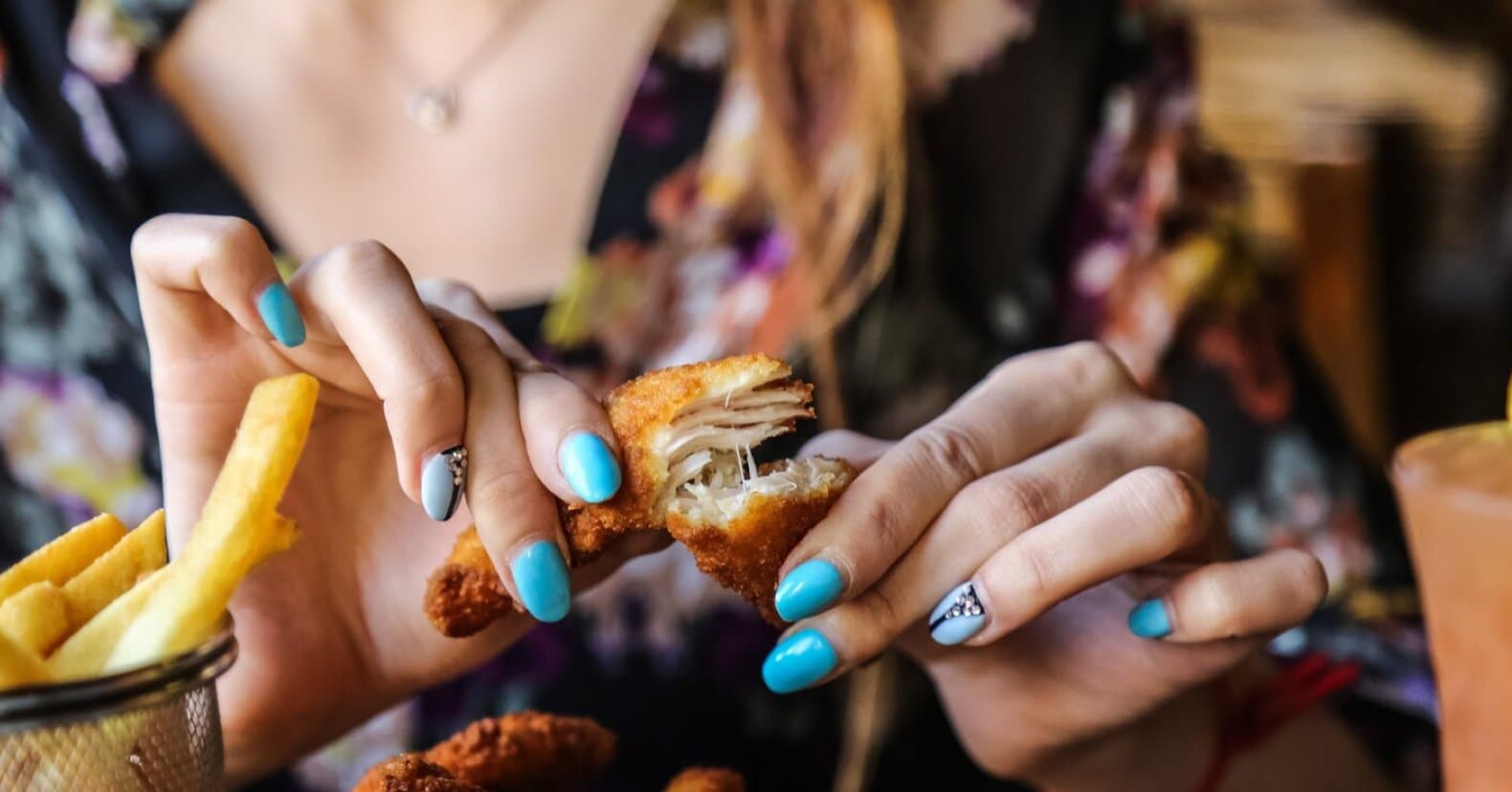 Hands pulling apart a crispy tender over fries