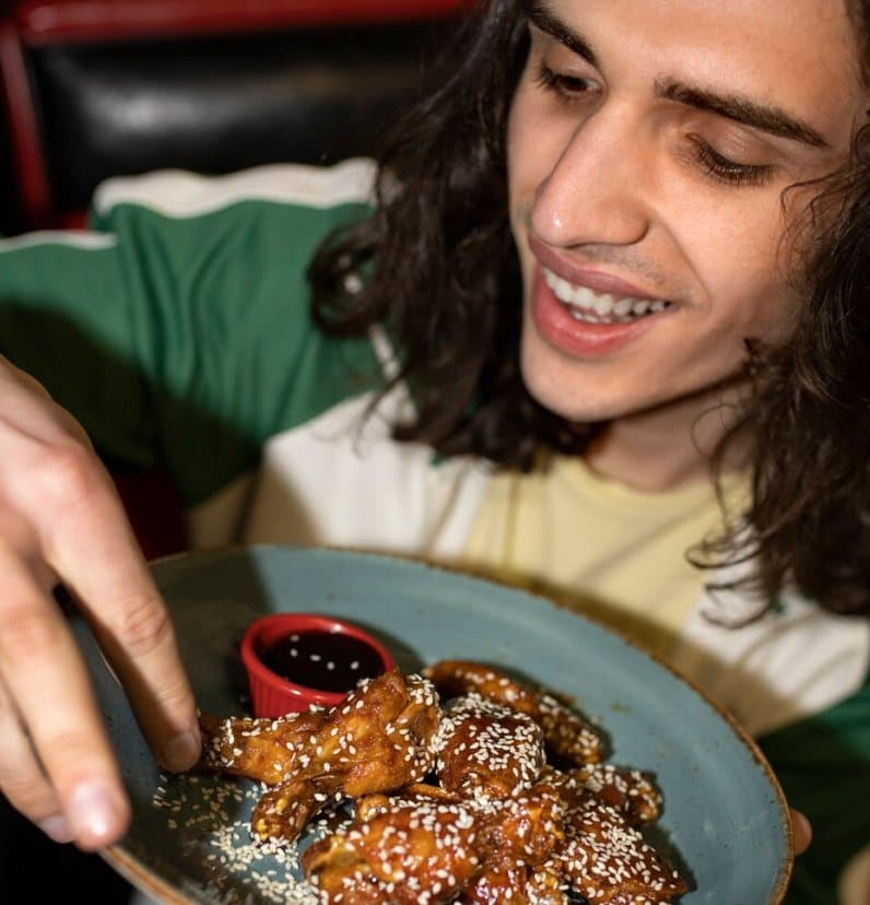 Smiling guest reaching for glazed wings